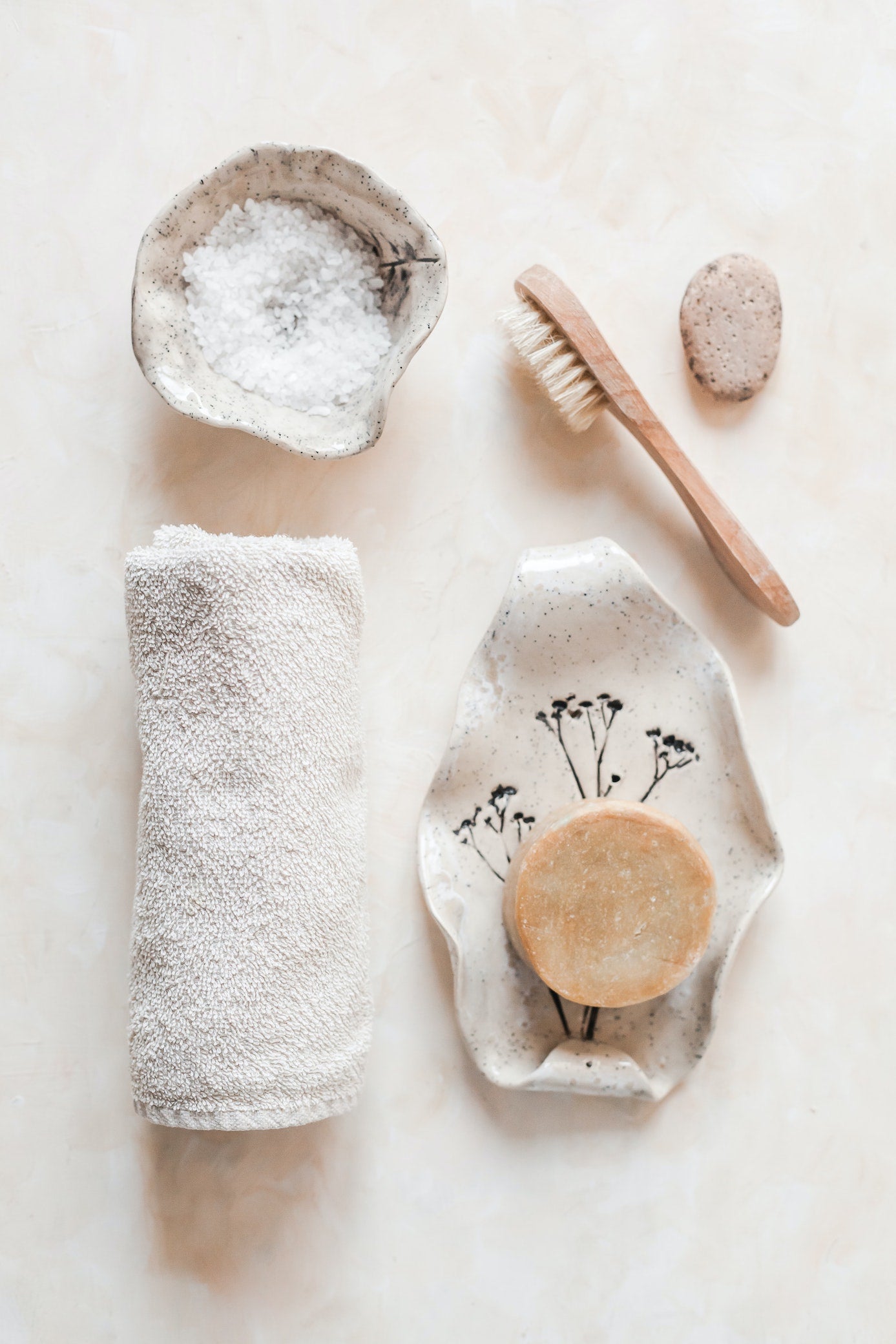 Items used for a nice bath, handmade soap, a towel, bath salts and a brush.